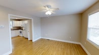 This multi-floor property spans three levels and presents a clean, functional interior designed for comfortable everyday living. The main living area is finished with warm light hardwood flooring that extends throughout, creating a bright and cohesive feel. Neutral grey-toned walls provide a versatile backdrop, complemented by crisp white trim and baseboards that frame each room neatly. A ceiling fan with an integrated light fixture is centrally mounted, offering both ventilation and ambient lighting to the living space.

Adjacent to the living area, the kitchen is visible through a wide doorway, featuring white cabinetry, white appliances including a refrigerator with an integrated ice and water dispenser, and a stove, all set against matching white finishes that keep the space feeling clean and bright. The kitchen layout appears efficient and well-organized, with ample cabinet storage.

The home's three-floor layout offers generous living space distributed across multiple levels, providing room for various living and sleeping arrangements. The overall ambiance is light, neutral, and move-in ready, with consistent finishes throughout that give the property a tidy, well-maintained character.