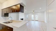 This well-designed single-story residence offers a thoughtfully planned layout across two bedrooms and two full bathrooms. The open-concept kitchen and living area serves as the heart of the home, featuring light hardwood flooring that runs seamlessly throughout. The kitchen is equipped with stainless steel appliances, rich dark-toned cabinetry, and a crisp white countertop with a breakfast bar overhang. The living room is bright and airy, with recessed lighting, a ceiling fan, a cozy fireplace, and double doors that invite natural light from outside. Both bedrooms are comfortably sized, featuring the same warm hardwood flooring, ceiling fans, and ample natural light from multiple windows. The spacious primary bedroom offers generous proportions and access to a well-appointed ensuite bathroom. Both bathrooms are finished with dark wood vanities, white quartz countertops, tub-shower combinations with white tile surrounds, and brushed nickel fixtures. The unit includes three closets—one of which is a large walk-in with built-in wire shelving—providing abundant storage. A dedicated laundry area and a hallway round out the functional floor plan, making this a complete and practical living space with a clean, modern aesthetic.