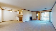 Located on Circle Ridge Road in Pewaukee, Wisconsin, this single-floor unit offers a practical and well-organized layout. The open living area serves as the heart of the space, highlighted by a stone-surround fireplace that adds a classic focal point to the room. Crown molding with warm wood-toned trim frames the walls throughout, lending a cohesive character to the interior. Neutral carpet flows through the living and bedroom areas, while a sliding glass door provides access to the outdoors and invites natural light into the main living space.

The kitchen is designed for functionality, featuring a peninsula with countertop seating, ample upper and lower cabinetry with wood-trimmed finishes, a built-in desk area, and included appliances such as a refrigerator and range. The kitchen opens directly to the living area, supporting an efficient, connected layout.

Multiple bedrooms are carpeted and naturally lit by windows with blinds, each equipped with baseboard heating. The bedrooms are generously proportioned and include closet access. The bathrooms feature tub and shower combinations, vanity storage, and tile flooring, maintaining a clean and functional aesthetic throughout the unit.