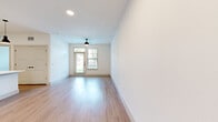 This thoughtfully designed one-bedroom, one-bathroom unit offers a clean, modern aesthetic across a single floor. Light-toned hardwood-style flooring flows continuously throughout the space, complementing the crisp white walls and creating a bright, cohesive atmosphere.

The open-concept living area is spacious and airy, featuring recessed lighting, a ceiling fan, and a glass-paned door with an adjacent window that invites abundant natural light and outdoor views. The kitchen is a standout feature, showcasing white shaker cabinetry with matte black hardware, white quartz countertops, a decorative hexagonal tile backsplash, and a full suite of stainless steel appliances including a gas range, over-the-range microwave, refrigerator with ice maker, and dishwasher. A large center island with pendant lighting above provides additional prep and seating space.

The bedroom is comfortably sized, with a ceiling fan, a large window overlooking greenery, and direct access to both the kitchen and the bathroom. The walk-in closet offers built-in shelving and hanging rods for ample storage organization.

The bathroom features a wide white vanity with a framed mirror, matte black fixtures, and a tub-shower combination adorned with elegant marble-style tile surround, blending style and function seamlessly.