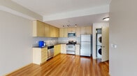 Located at 1450 N Prescott St in Portland, Oregon, this well-designed one-bedroom, one-bathroom residence offers a functional and modern layout across a single floor. The open-concept kitchen and living area serves as the heart of the home, featuring warm hardwood flooring that extends throughout the main living spaces. The kitchen is well-appointed with light maple cabinetry, dark countertops, a full suite of stainless steel appliances including a refrigerator, electric range, microwave, and dishwasher, as well as a convenient in-unit stacked washer and dryer. Track lighting overhead adds a contemporary touch to the space. The living area provides a bright, open canvas with clean neutral walls and generous natural light from a large sliding glass door. The bedroom is a comfortable, carpeted retreat featuring a window with outdoor views, a built-in closet, and a baseboard heater. A hallway connects the main living areas and leads to the full bathroom, which includes a tub/shower combination, a light wood vanity, and tile flooring. The overall design is clean, modern, and practical, making this an efficient and inviting residence in North Portland.