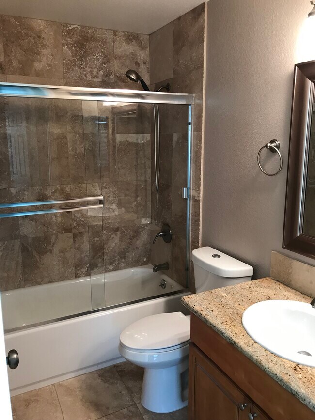 Tiled Hallway bathroom with tub and granite countertop - 6975 Rodling Dr