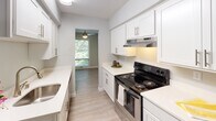 Located along US-12 in Wayzata, Minnesota, this single-floor residence offers a well-organized layout with updated finishes throughout. The spacious living area serves as the centerpiece of the home, featuring wood-style hard flooring, neutral gray walls, and a textured ceiling. Large vertical blinds frame a sliding glass door that invites natural light and provides views of the surrounding greenery, while an additional window further brightens the space. A ceiling fan fixture adds both function and visual interest to the room.

The galley-style kitchen is efficiently designed with white shaker cabinetry, light quartz countertops, a stainless steel sink, and a stainless electric range with an overhead ventilation hood. Light wood-style flooring runs through the kitchen, which opens directly into the main living area for a connected feel.

The bedroom features plush carpeting, soft neutral tones, a textured ceiling, and a window that allows natural light to filter in. The full bathroom is clean and bright, with white cabinetry, a white countertop vanity, wood-style flooring, and a tiled tub-shower combination. The overall aesthetic is fresh, cohesive, and move-in ready.