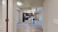 This contemporary single-floor residence offers a thoughtfully designed open layout that seamlessly connects the main living and kitchen areas. The kitchen is a standout feature, showcasing dark espresso cabinetry with sleek hardware, a mosaic tile backsplash, stainless steel appliances including a French door refrigerator, microwave, and range, all complemented by a generous center island with a white countertop and undermount sink. Pendant lighting and recessed fixtures illuminate the space with a modern flair. Light wood-look flooring flows consistently throughout the entire unit, lending a cohesive and clean aesthetic. The living area is bright and open, benefiting from natural light through large windows and featuring a ceiling fan overhead. The bedrooms are well-proportioned, each with ceiling fans, wide windows fitted with blinds that invite natural light, and ample wall space. The primary bathroom features an extended dual-sink vanity with dark cabinetry and white countertops, a barn-style sliding door, and a clean, functional layout. A secondary bathroom mirrors the same modern style. A dedicated laundry room with full-size washer and dryer adds everyday convenience. Overall, the space presents a polished, contemporary design with consistent finishes throughout.