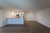 Located on Live Oak Street in Hesperia, California, this single-story unit offers a clean, modern aesthetic defined by light wood-style flooring, crisp white walls, and recessed lighting throughout. The open-concept living and kitchen area forms the heart of the space, where a peninsula with bar seating separates the two zones while maintaining a seamless, airy feel. The kitchen is well-appointed with white cabinetry, light countertops, stainless steel appliances including a refrigerator, range, microwave, and dishwasher, all illuminated by recessed ceiling lights.

The living area is generously proportioned, featuring a sliding glass door fitted with vertical blinds that allows natural light to filter in. The bedrooms continue the consistent flooring and neutral palette, each offering multiple windows dressed with horizontal blinds that bring in ample daylight and views of the surrounding area. Closet space is provided within the bedrooms for practical storage.

Two bathrooms serve the unit. One features a tub and shower combination with a wall-mounted sink and mirror, while the second is equipped with a sliding glass shower enclosure, a white vanity with an integrated sink, and a window for natural ventilation. Both bathrooms maintain the clean, minimalist design found throughout the rest of the space.