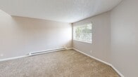 Located in Beaverton, Oregon, this three-bedroom, one-bathroom unit offers a practical and comfortable single-floor layout. The combined living and dining area provides an open, flexible space with neutral-toned carpet, a textured ceiling, and a ceiling fan, creating a welcoming atmosphere. Natural light filters in through windows offering views of surrounding greenery.

The galley-style kitchen is well-appointed with white cabinetry, dark countertops, and a full suite of white appliances including an electric range and refrigerator. Light wood-look flooring runs throughout the kitchen and hallway, providing a clean contrast to the carpeted living and sleeping areas.

The three bedrooms are each carpeted and feature textured ceilings, neutral wall tones, and baseboard heating. Several bedrooms include closets, and the primary bedroom is generously sized with a sliding-door closet and a window overlooking mature trees. The unit is equipped with six closets in total, offering ample storage throughout.

The bathroom includes a tub-shower combination and wood-look flooring. A dedicated laundry area and a private balcony round out the unit's amenities, adding both convenience and outdoor access to this well-organized Beaverton residence.