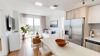 Located in Pompano Beach, FL, this thoughtfully designed 2-bedroom, 2-bathroom residence offers a clean, modern aesthetic throughout its efficiently organized single-floor layout. The open-concept living and kitchen area serves as the heart of the home, bathed in natural light from large sliding glass doors that lead to a private balcony with expansive outdoor views of the surrounding cityscape. The living room features warm hardwood-style flooring, sheer neutral drapery, and a coastal-inspired ambiance that complements the South Florida setting.

The kitchen is well-appointed with stainless steel appliances — including a French door refrigerator, electric range, microwave, and dishwasher — paired with two-tone cabinetry in white and light wood finishes, white quartz countertops, and a central island that doubles as a dining area. Track lighting overhead adds a modern touch.

Both bedrooms are carpeted and filled with natural light from large windows framing open sky views. The primary bedroom offers a comfortable and serene retreat with ample space. The two bathrooms are finished with large-format tile, including a soaking tub and shower combination. A hallway and closet complete the functional layout of this well-appointed coastal residence.
