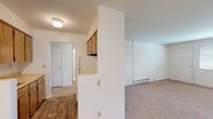 Baldwin Manor F25 is a single-floor unit offering a practical and well-organized layout. The kitchen is equipped with warm oak cabinetry, a coil-burner electric range, and a full-size refrigerator, complemented by laminate countertops that provide ample workspace. A pass-through opening connects the kitchen to the rest of the unit, enhancing the sense of openness between spaces. The living area is generously proportioned, featuring neutral wall-to-wall carpeting, baseboard heating, and a wall-unit air conditioner, ensuring year-round comfort. A window with blinds allows natural light to fill the room. The bedroom is well-sized with the same plush carpeting and benefits from a dedicated walk-in closet, offering substantial storage. Baseboard heating and a wall-unit air conditioner are present here as well, along with a window that brings in additional natural light. The bathroom is clean and efficiently designed, featuring a tiled tub-and-shower combination, a vanity with under-sink cabinet storage, a mirrored medicine cabinet, and white tile flooring. Throughout the unit, the white walls and neutral finishes create a bright, move-in-ready environment that is easy to personalize.