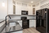 Located on Seabiscuit Lane in Greensboro, NC, this single-floor residence offers a well-designed layout with a variety of living spaces visible across a detailed floor plan. The kitchen serves as a central highlight, showcasing tall white shaker cabinetry extending to the ceiling, a classic white subway tile backsplash, dark granite countertops, and a built-in wine rack. Black GE appliances—including a side-by-side refrigerator, range, and over-the-range microwave—create a bold contrast against the bright cabinetry. A peninsula with matching granite provides additional prep and seating space, while pendant lighting and recessed fixtures illuminate the area. A walk-in pantry is conveniently located adjacent to the kitchen.

Light wood-look flooring runs throughout the main living and kitchen areas, while bedrooms feature plush wall-to-wall carpet. Bedrooms are generously sized with neutral walls, ceiling fans, and windows that allow natural light. Several bedrooms offer direct access to bathrooms, one of which includes a framed glass walk-in shower, white vanity cabinetry, and granite countertops. A dedicated laundry room provides wire shelving and utility hookups. Crown molding and clean white trim are consistent throughout, contributing to a polished, cohesive interior aesthetic.