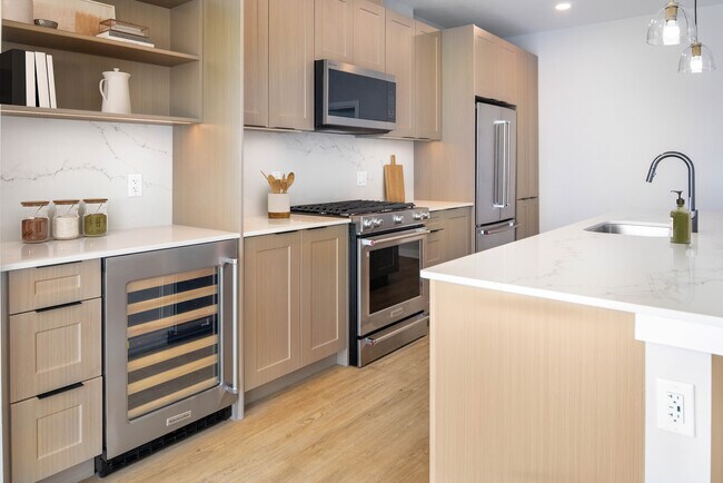 Cocina Signature Collection con gabinetes estilo shaker de roble, encimera de cuarzo blanco marmolado y electrodomésticos de acero inoxidable renovados. - Avalon W Squared