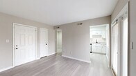 Located at 14505 Old Courthouse Way in Newport News, Virginia, this single-floor home offers four bedrooms and two full bathrooms with a clean, modern aesthetic throughout. The open living area features light wood-style luxury vinyl flooring, neutral warm-gray walls, crisp white trim, and access to the outdoors through a glass-paneled door that fills the space with natural light. The adjacent kitchen is well-appointed with white shaker-style cabinetry, light granite countertops, a stainless steel dishwasher, a matte black faucet, and a window overlooking the exterior. Two hallways connect the living spaces to the four bedrooms, which feature plush neutral carpeting, ample natural light from windows with blinds, and closet access. The primary bedroom offers a comfortable and private retreat. Both bathrooms are finished in a contemporary style — one features a white vanity with a matte black faucet and matching towel ring hardware paired with a large mirror, while the other includes a full tub-shower combination with matte black fixtures. The consistent use of neutral tones, black accent hardware, and clean lines gives the entire home a cohesive and modern feel.
