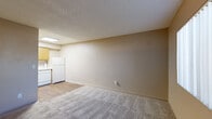 Located at 6775 E Golf Links Rd in Tucson, Arizona, this one-bedroom, one-bathroom unit offers a compact and efficiently arranged single-floor layout. The open living area features neutral beige walls, plush wall-to-wall carpeting, and a textured ceiling, creating a simple and functional atmosphere. A wall-mounted HVAC unit and a large window with vertical blinds provide comfort and natural light. The kitchen flows directly from the living space and is equipped with oak-toned cabinetry, a white electric range, a dishwasher, and a refrigerator, all set on durable wood-style flooring that contrasts cleanly with the carpeted living areas. The bedroom is a comfortably sized private retreat, featuring carpet flooring, a ceiling fan with light fixture, a window that brings in natural light, and access to a dedicated closet. A hallway connects the bedroom to the full bathroom, which includes a single-sink vanity with wood-tone cabinetry, a wall mirror with built-in shelving, a toilet, and a full-size tub and shower combination. Throughout the unit, the warm neutral color palette and functional finishes contribute to a straightforward, move-in-ready living environment suited for individuals or couples seeking practical accommodations in Tucson.
