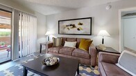 Located at 9415 N 99th Ave in Peoria, Arizona, this single-story residence offers a thoughtfully designed layout across one bedroom and two bathrooms. The galley-style kitchen is outfitted with sleek gray cabinetry, white countertops, stainless steel appliances—including a refrigerator, range, and over-the-range microwave—and wood-look flooring that extends into the adjacent dining area. The dining space is an intimate nook with neutral walls, ideal for everyday meals. The living room features vertical blinds, a sliding glass door that opens to a covered outdoor patio, and a cozy, welcoming ambiance with ample natural light. The bedroom is carpeted and generously sized, equipped with a ceiling fan, a large window with vertical blinds, and a dedicated closet. The primary bathroom includes a long dual-sink vanity with dark gray cabinetry, a large mirror, and wood-look flooring, while a secondary bathroom offers a full tub and shower combo. Neutral tones, textured ceilings, and consistent finishes throughout create a cohesive and comfortable living environment suited for those seeking a practical yet stylish home in the Peoria area.