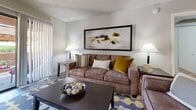 Located at 9415 N 99th Ave in Peoria, Arizona, this single-story residence offers a thoughtfully designed layout across one bedroom and two bathrooms. The galley-style kitchen is outfitted with sleek gray cabinetry, white countertops, stainless steel appliances—including a refrigerator, range, and over-the-range microwave—and wood-look flooring that extends into the adjacent dining area. The dining space is an intimate nook with neutral walls, ideal for everyday meals. The living room features vertical blinds, a sliding glass door that opens to a covered outdoor patio, and a cozy, welcoming ambiance with ample natural light. The bedroom is carpeted and generously sized, equipped with a ceiling fan, a large window with vertical blinds, and a dedicated closet. The primary bathroom includes a long dual-sink vanity with dark gray cabinetry, a large mirror, and wood-look flooring, while a secondary bathroom offers a full tub and shower combo. Neutral tones, textured ceilings, and consistent finishes throughout create a cohesive and comfortable living environment suited for those seeking a practical yet stylish home in the Peoria area.