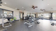 Located at 2252 N 44th St in Phoenix, AZ, this fitness center is a single-story facility thoughtfully designed to support a full range of workout routines. The space is divided into two dedicated exercise rooms connected by a hallway, offering users distinct zones for different types of training.

The main exercise room is generously proportioned, featuring durable rubberized flooring, recessed lighting, and ceiling fans that maintain air circulation throughout. Large arched windows invite abundant natural light and provide views of the surrounding outdoor environment, creating an open and energizing atmosphere. This room is equipped with a full rack of dumbbells, a Smith machine, weight benches, and a variety of cable and resistance machines, making it well-suited for comprehensive strength training.

A second exercise room provides dedicated space for cardio equipment, including treadmills and elliptical machines from True Fitness, all positioned in front of expansive arched windows. Wall-mounted televisions and additional ceiling fans enhance the comfort of this space. A connecting area features a spin bike and additional True treadmills, accented by a vibrant teal accent wall that adds a bold, motivating touch. Crown molding and full-wall mirrors throughout lend a polished finish to the facility, amplifying the sense of space and supporting proper form during workouts.