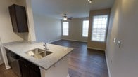 Located at 1211 Gray Birch Way in Knoxville, Tennessee, this two-floor home offers a well-designed layout with thoughtful finishes throughout. The main living area is anchored by an open-concept design that seamlessly connects the kitchen and living room, creating an inviting and functional space ideal for everyday living and entertaining.

The kitchen is appointed with dark espresso cabinetry that extends to the ceiling for ample storage, granite-style countertops, and a double stainless steel sink set into a peninsula that overlooks the living area. Stainless steel appliances, including a refrigerator, gas range, and built-in microwave, complement the rich cabinetry. Track lighting illuminates both the kitchen and the peninsula, adding a modern touch.

The living room is generously proportioned, featuring rich hardwood-style flooring, a ceiling fan with light fixture, and multiple large windows that flood the space with natural light and provide views of the surrounding neighborhood. The neutral wall tones throughout lend the home a clean, versatile aesthetic.

The staircase connects the two floors, with the upper level housing additional rooms visible in the floor plan model. The garage provides substantial enclosed storage or parking space. Overall, this home combines practical design with quality finishes to deliver a comfortable and well-lit living environment.