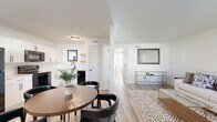 This 760 square foot single-story home offers a well-designed layout with three bedrooms and one bathroom. The interior is characterized by a modern aesthetic, featuring light-toned wood flooring throughout and crisp white walls that create a bright, airy atmosphere.

The living room is inviting, with a comfortable sofa and armchair arranged around a stylish glass coffee table. A patterned area rug adds warmth and texture to the space. Natural light floods in through windows, enhancing the room's openness.

The primary bedroom, measuring 140 square feet, includes a ceiling fan for comfort and ample natural light from a large window. Built-in closets provide storage space. The additional bedrooms are similarly appointed, with one featuring decorative wall art.

The bathroom showcases a clean, contemporary design with a white vanity, toilet, and shower/tub combination. Black fixtures add a modern touch, while wood-look flooring continues the home's cohesive design.

The kitchen, while compact, is efficiently designed with white cabinetry, stainless steel appliances, and a small dining area. Open shelving adds both storage and visual interest.

Throughout the home, ceiling fans aid in air circulation, and window blinds offer privacy and light control. The overall design emphasizes functionality and style, making excellent use of the available space in this cozy urban dwelling.