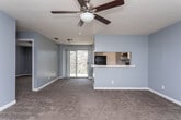 Located at 100 Tallokas Ct in Leesburg, Georgia, this single-floor residence offers a well-organized layout with a cohesive design throughout. The interior is finished in a consistent cool gray-blue palette, complemented by white trim and neutral carpeting across the main living and bedroom areas.

The open living room is generously proportioned, featuring a ceiling fan with light fixture and a textured ceiling. A sliding glass door at the far end floods the space with natural light and provides direct access to an outdoor balcony. The living area connects seamlessly to the kitchen via a pass-through counter, creating an open and communicative floor plan.

The kitchen is fully equipped with black appliances — including a refrigerator, electric range, and dishwasher — set against crisp white cabinetry and white countertops. Tile flooring in a warm beige tone adds durability and easy maintenance to the space.

The bedroom is a comfortable, carpeted retreat with a ceiling fan, a window allowing in natural light, and direct access to a walk-in closet with built-in shelving. An additional bedroom provides similar comfort with carpeted floors and a bright window.

The bathroom features tile flooring matching the kitchen, a single-sink vanity with a mirror, a full soaking tub and shower combo, and cool gray walls that tie the space together with the rest of the home's palette.