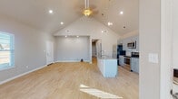 Located at 1000 Zachary St in Centerton, Arkansas, this single-story home showcases a thoughtfully designed open-concept floor plan that seamlessly connects the living, dining, and kitchen areas. The great room is defined by dramatic vaulted ceilings that rise to an impressive peak, complemented by recessed lighting, a ceiling fan, and light wood-look flooring that flows throughout. Natural light filters in through multiple windows fitted with blinds, enhancing the home's airy atmosphere. The kitchen is a functional centerpiece, featuring soft gray shaker-style cabinetry, granite countertops, a center island with a built-in sink, stylish pendant lighting, and a full suite of stainless steel appliances including a refrigerator, range, and over-the-range microwave. The primary bedroom offers a ceiling fan, a walk-in closet with built-in shelving, and direct access to additional rooms. A full bathroom includes a tub/shower combo and a wall-mounted cabinet. The attached garage provides generous storage space, concrete flooring, recessed lighting, an automatic opener, and a dedicated electrical panel. This move-in-ready home delivers a clean, modern aesthetic throughout.