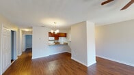 This single-story residence is designed with an open, flowing layout that connects the main living areas seamlessly. Rich, dark hardwood-style flooring extends throughout the entire unit, providing a cohesive and warm aesthetic in every room. Textured ceilings and clean white baseboards complement the neutral wall tones, creating a bright and inviting atmosphere.

The spacious living room is a standout feature, anchored by a tiled fireplace with a classic hearth surround. Large sliding glass doors dressed with vertical blinds flood the room with natural light and provide outdoor access. A ceiling fan with a light fixture adds both function and comfort to this central gathering space.

The kitchen features warm wood cabinetry, a peninsula breakfast bar with a laminate countertop, and white appliances including a built-in microwave and range. A chandelier overhead defines the adjacent dining area, which is separated from the living room by a structural column.

The bedrooms are generously sized, each equipped with ceiling fans and sliding glass doors or windows with vertical blinds. The bathroom includes a tiled tub-and-shower combination, wood-toned vanity cabinetry, and granite-style countertops. Additional highlights include a walk-through closet connecting the bathroom to the primary bedroom.