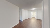 Located at 4901 Wornall Rd in Kansas City, Missouri, this two-bedroom, two-bathroom residence offers a well-organized single-floor layout with a clean, neutral aesthetic throughout. Rich, dark hardwood-style flooring runs through the main living areas, creating a warm contrast against bright white walls and trim.

The spacious living room is a standout feature, anchored by a large floor-to-ceiling sliding glass door that floods the room with natural light and opens directly onto a private patio. The patio offers pleasant views of mature trees and the surrounding neighborhood greenery. An adjacent dining room provides a defined space for meals, flowing naturally from the living area.

The kitchen is efficiently designed in an L-shaped configuration, outfitted with white cabinetry, a subway tile backsplash, and a full suite of white appliances including a refrigerator, electric range, built-in microwave, and dishwasher. The space is bright and functional.

The generously sized primary bedroom features plush carpeting, a sliding glass door with outdoor access, and ample wall space. The second bedroom is equally comfortable with soft carpeting and good natural light. Both bathrooms are clean and simply appointed, with one featuring a full tiled soaking tub. Four closets throughout the unit ensure abundant storage. A dedicated entrance and hallway complete this thoughtfully laid-out home.