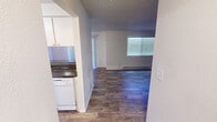 This single-floor unit at 22850 30th Ave S in Des Moines, Washington, offers a practical and straightforward layout suited for comfortable everyday living. The interior is finished with neutral tones throughout, creating a clean and cohesive aesthetic.

The kitchen is equipped with white cabinetry providing ample storage, dark granite-style countertops, a white electric range, dishwasher, and a built-in range hood. The layout flows efficiently, connecting the kitchen to the main living area via an open passageway. The living room is generously sized, featuring wood-style plank flooring, a textured ceiling, a baseboard heating unit, and a window fitted with horizontal blinds that allows natural light to fill the space.

The bedroom is carpeted for added comfort and includes its own window with blinds and a baseboard heater, making it a well-lit and climate-controlled space. The bathroom features a full tub and shower combo with clean white surround panels and chrome fixtures.

Throughout the unit, wood-style flooring unifies the main areas, while textured ceilings add architectural character. The overall layout, as seen in the 3D model, is compact yet efficiently organized for functional single-floor living.
