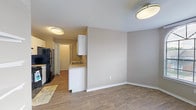 Located at 1303 S Main St in Duncanville, Texas, this single-story residence offers a well-designed layout with a variety of functional and comfortable living spaces. The living room is a standout area, featuring soaring vaulted ceilings, warm neutral-toned carpet, and a tile-surround fireplace with glass doors that serves as a natural focal point. Natural light fills the space through a large window and sliding glass door that opens directly onto a private patio, providing pleasant outdoor views. The kitchen is efficiently designed with white cabinetry, granite-style countertops, and black appliances including a range and refrigerator, all set above durable wood-look flooring that continues through the main areas. A dedicated dining area flows seamlessly from the kitchen, enhanced by flush-mount lighting and an open feel. The bedroom is generously sized with plush carpet, a ceiling fan, and a charming bay window that brings in abundant natural light. The bathroom is cleanly finished with tile-surround tub and shower, a white vanity with granite countertop, and wood-look flooring. A dedicated in-unit laundry area with shelving accommodates full-sized washer and dryer units, adding everyday convenience to this thoughtfully appointed residence.