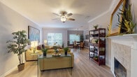 This thoughtfully designed single-floor residence offers a seamless blend of comfort and functionality across a variety of well-defined living spaces. The open-concept living and dining area serves as the heart of the home, featuring light hardwood-style flooring, crown molding, and a ceiling fan that enhances airflow and ambiance. Large windows fitted with blinds invite an abundance of natural light while maintaining privacy. The living room accommodates generous seating and is complemented by an adjacent dining area with decorative wainscoting, a stylish drum pendant light, and a glass-top table — a refined space for entertaining.

The kitchen is equipped with stainless steel appliances, white shaker-style cabinetry, granite countertops, and a substantial island with seating, making it both practical and visually appealing. A dedicated office or flex room with multiple windows and hardwood-style flooring provides a quiet retreat for work or reading.

The primary bedroom features a tray ceiling, ceiling fan, warm accent wall, and ample natural light. The bathroom includes a tiled tub-and-shower combination enclosed by sleek sliding glass doors. A dedicated laundry area with a full-size washer and dryer adds everyday convenience to this well-rounded home.