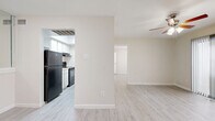 This efficient and thoughtfully laid-out one-bedroom, one-bathroom residence offers a clean, neutral aesthetic throughout its single floor. Light wood-style flooring flows seamlessly across all living areas, complementing the warm beige walls and bright white trim that define the space's cohesive look.

The open living area is anchored by a ceiling fan and receives natural light through a sliding glass door fitted with vertical blinds, providing direct access to an outdoor area. The galley-style kitchen is positioned adjacent to the living room and features white cabinetry, a granite-style countertop, a stainless steel sink, and black appliances including a refrigerator, range, and dishwasher. An overhead skylight lends additional brightness to the kitchen.

The bedroom is a comfortable, well-proportioned room with its own ceiling fan and a window with blinds that allows natural light. A spacious walk-in closet off the bedroom offers dual-sided shelving and hanging rods, providing generous storage capacity. The full bathroom includes a tub-shower combination with white tile surround, a granite-style vanity countertop, and wood-style flooring. The unit is further complemented by an in-unit laundry area and a hallway that connects the main living spaces efficiently.