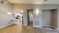 Located at 5533 Sunlight Dr in Durham, NC, this single-floor, 3-bedroom, 2-bathroom home offers a practical and well-appointed layout. The open-concept kitchen and living room serve as the heart of the home, featuring light wood-look flooring and neutral warm-gray tones throughout. The kitchen is equipped with stainless steel appliances—including a range, microwave, and refrigerator—complemented by white shaker-style cabinetry, light quartz countertops, a subway tile backsplash, and a peninsula that provides additional prep and seating space. The living room receives ample natural light through a large window and glass door that opens to an outdoor area. A central hallway connects the bedrooms and bathrooms, with wall sconces providing ambient lighting. The primary bedroom is a comfortable size, featuring plush carpet, a ceiling fan, a window for natural light, and a dedicated closet. The additional bedrooms also feature carpet flooring and neutral walls, ideal for flexible use. Both bathrooms are finished with wood-look tile flooring, white vanities with bright vanity lighting, and mirrors. One bathroom includes a tiled soaking tub and shower combination. Three closets throughout the home offer generous storage solutions.