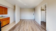 Located on the 12th floor at 5340 Delmar Blvd in St. Louis, Missouri, unit 1203 is a single-floor residence that combines an open, airy layout with practical finishes throughout. The main living area is generously proportioned, featuring light wood-style flooring that runs continuously through the space, bright white walls, and a large picture window that frames sweeping views of the surrounding cityscape and treetops, allowing abundant natural light to fill the room.

The kitchen is positioned adjacent to the living area in a semi-open configuration, separated by a partial wall and a breakfast bar with a wood-tone countertop. It is equipped with warm honey-toned wood cabinetry, a gas range, granite-style countertops, and tile flooring. A window unit provides climate control, and a separate window brings additional natural light into the kitchen area.

The bedroom offers a clean, neutral palette with the same wood-style flooring, a closet, and ample wall space. The bathroom retains a classic design with white subway-style tile wainscoting accented by a light blue tile border, a full soaking tub with shower, a pedestal sink, and a frosted privacy window. The overall ambiance of the unit is bright, clean, and functional, well-suited for comfortable urban living in the Delmar Boulevard corridor.