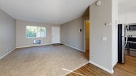 Located at 2209 E Santa Clara Ave in Santa Ana, California, this single-story unit presents a clean, neutral aesthetic with a practical, open layout. The living area is generously sized, featuring plush carpet flooring, a textured ceiling, and a ceiling fan that promotes air circulation. Vertical blinds cover a large sliding glass door or window, allowing natural light to fill the space while offering privacy control. A transition to wood-look hard flooring defines the adjacent dining or entryway area, adding visual contrast and easy maintenance underfoot.

The kitchen is a standout feature, outfitted with white shaker-style cabinetry, light stone-patterned countertops, and a mosaic tile backsplash. A full suite of stainless steel appliances—including a refrigerator, range, over-the-range microwave, and dishwasher—provides modern functionality. Wood-look flooring runs throughout the kitchen, complementing the bright, clean design. A window above the sink brings in natural light.

The bathroom is straightforward and well-maintained, featuring a full tub-shower combination with brushed nickel fixtures, a toilet, and wood-look flooring. Clean white walls and simple hardware give the space a crisp, utilitarian feel. Overall, the unit offers a bright, move-in ready environment in a convenient Southern California location.