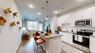 Located on Garron Point Drive in Charlotte, NC, this single-floor, 2-bedroom, 2-bathroom residence offers a well-organized layout that balances functionality with contemporary design. Wood-style flooring runs throughout the space, providing a cohesive and warm aesthetic that unifies each room.

The kitchen is a standout feature, showcasing white shaker cabinetry, a white subway tile backsplash, quartz countertops, and a full suite of stainless steel appliances. A central island with seating and dual pendant lighting makes the kitchen both practical and visually appealing. It opens fluidly into the living room, which benefits from a large window allowing ample natural light and features a ceiling fan overhead.

The primary bedroom is a comfortable retreat with two windows that invite natural light, a ceiling fan, and convenient closet storage. The second bedroom similarly offers a bright window, closet space, and a ceiling fan. Each bathroom reflects a clean, modern aesthetic—one features a marble-style tiled tub-shower combination, while the other offers a walk-in shower with matching tile and a sliding glass door. Neutral tones and recessed lighting throughout contribute to the space's bright, contemporary ambiance.