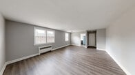 This single-floor residence offers a thoughtfully designed layout with a cohesive, modern aesthetic throughout. The living areas are generously proportioned, featuring light gray luxury vinyl plank flooring that extends seamlessly across the space, complemented by crisp white baseboards and neutral gray walls that create a bright, welcoming atmosphere. Large windows in the living and dining areas allow abundant natural light to fill the rooms while offering views of the surrounding neighborhood. Radiator heating units are positioned beneath the windows in several rooms, providing efficient warmth.

The kitchen is well-equipped with a stainless steel gas range, a classic white subway tile backsplash, white cabinetry, and a window that brings in additional natural light. A full-size refrigerator is also present, completing the functional kitchen setup.

The bedrooms are comfortably sized, with one featuring dual closets and continued hardwood-style flooring. Windows in the bedrooms provide cross-ventilation and outdoor views. The bathroom is cleanly finished with white tile walls and flooring, a soaking tub, a dark wood vanity with a marble-topped sink, and a window for natural light. Overall, the space presents a clean, move-in ready environment with a neutral palette suited to a variety of interior styles.