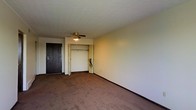 Located at 4645 Tamarack Blvd in Columbus, Ohio, this single-floor unit offers a straightforward and functional layout designed for comfortable everyday living. The main living area is finished with wall-to-wall carpeting in a warm, neutral tone, providing a cozy and inviting atmosphere throughout. A ceiling fan with integrated lighting is centrally mounted, ensuring consistent air circulation and ambient illumination across the space. The room features clean, light-colored walls that contribute to a bright and open feel. A dark-toned entry door provides a bold contrast to the lighter interior palette, marking a clear and defined entryway into the unit. Adjacent to the main living area is a generously sized closet, offering ample storage capacity with an open rod system readily visible. The layout is practical and efficient, making good use of the available floor space. Textured ceilings add a subtle architectural detail overhead. Overall, the unit presents a clean, neutral canvas well-suited for personalization, situated in a convenient Columbus location with easy access to nearby amenities along the Tamarack Boulevard corridor.