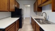 This single-floor unit offers a practical and comfortable layout across several well-defined living spaces. The living area is bright and open, featuring light wood-style laminate flooring, neutral gray walls, a wall-mounted air conditioning unit, and a sliding glass door that allows natural light to flow in while providing outdoor access. Baseboard heating runs throughout much of the unit, ensuring consistent warmth.

The galley-style kitchen is efficiently designed with rich, warm wood cabinetry lining both sides, light-toned countertops, a stainless steel sink, and black appliances including a full-size refrigerator. The kitchen opens to an adjacent hallway, creating a natural flow through the unit.

The bedrooms are carpeted in neutral tones and feature textured ceilings, baseboard heating, and windows with blinds that offer both natural light and privacy. One bedroom also includes a wall-mounted air conditioning unit for additional climate control.

Additional rooms feature the same light wood-style laminate flooring, clean white walls, and flush-mount ceiling lighting, lending a consistent and cohesive aesthetic throughout.

The bathroom is straightforward and functional, complete with a full tub-shower combination, a toilet, and wood-style flooring. Overall, the unit presents a clean, move-in-ready environment with consistent finishes throughout.