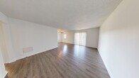 This 1-bedroom, 1-bathroom unit at 2215 Sumpter St in Hoover, Alabama offers a clean, modern interior across a single floor. The open living area is a standout feature, finished with rich hardwood-style flooring that reflects natural light pouring in through large vertical-blind-covered sliding glass doors. A ceiling fan anchors the space, contributing to both comfort and airflow. The neutral white walls and textured ceilings throughout lend a bright, cohesive aesthetic.

The kitchen is efficiently laid out with white cabinetry, granite-look countertops, a subway tile backsplash, a stainless steel sink, and white appliances including a range and dishwasher. Light wood-style flooring carries through this space seamlessly.

The bedroom is generously sized, featuring soft carpeting, a natural window for daylight, and access to a walk-in closet, providing ample storage. A second doorway connects conveniently to the rest of the unit.

The bathroom is well-appointed with a granite-topped vanity, a wide mirror, hardwood-style flooring, and a full-size soaking tub with a shower rod. The layout is practical and clean. Overall, the unit presents a well-maintained, move-in-ready living space in a convenient Hoover location.