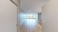 Located at 1850 Green Bay Rd in Highland Park, IL, this well-appointed 2-bedroom, 2-bathroom residence offers a generous, thoughtfully designed floor plan across a single level. The open-concept kitchen and living area serves as the heart of the home, featuring light hardwood flooring, white shaker cabinetry, a herringbone tile backsplash, stainless steel appliances, and a center island with pendant lighting — ideal for both everyday living and entertaining. The living room extends naturally toward floor-to-ceiling sliding glass doors that lead to a private balcony finished with warm wood decking and a glass railing, offering elevated views of the surrounding Highland Park neighborhood. Both bedrooms are carpeted and bathed in natural light from large windows, with the primary bedroom providing a comfortable and sizable retreat. Two well-organized closets offer ample storage. The bathrooms are finished in a clean, contemporary style, featuring large-format white tile flooring, glass-enclosed walk-in showers, and sleek white vanities with modern hardware. Hallways connect the spaces efficiently, maintaining a cohesive, neutral palette of soft grays and whites throughout that contributes to a bright, modern ambiance.