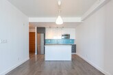 Located at 109 Vaughan Rd in Toronto's midtown neighbourhood, this well-designed one-bedroom, one-bathroom unit offers a thoughtfully laid-out single-floor plan. The open-concept kitchen and living area serves as the heart of the space, showcasing a modern kitchen equipped with two-tone cabinetry — white uppers paired with dark lower cabinets — a vibrant turquoise tile backsplash, stainless steel appliances including a built-in microwave and refrigerator, a sleek countertop sink, and a central island with a quartz surface that provides additional prep space and casual seating. Track lighting and a pendant fixture illuminate the area warmly. Light hardwood flooring flows throughout, lending a clean, cohesive aesthetic. Built-in open shelving near the living area offers functional storage and display space. The bedroom is a bright, serene retreat featuring a large sliding window that frames an open rooftop view and fills the room with natural light. The full bathroom is finished in crisp white tile with a soaker tub and adjustable shower fixture. Two hallways connect the rooms efficiently, and the overall palette of whites and neutrals creates a fresh, contemporary ambiance throughout.