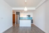 Located at 109 Vaughan Rd in Toronto's midtown neighbourhood, this well-designed one-bedroom, one-bathroom unit offers a thoughtfully laid-out single-floor plan. The open-concept kitchen and living area serves as the heart of the space, showcasing a modern kitchen equipped with two-tone cabinetry — white uppers paired with dark lower cabinets — a vibrant turquoise tile backsplash, stainless steel appliances including a built-in microwave and refrigerator, a sleek countertop sink, and a central island with a quartz surface that provides additional prep space and casual seating. Track lighting and a pendant fixture illuminate the area warmly. Light hardwood flooring flows throughout, lending a clean, cohesive aesthetic. Built-in open shelving near the living area offers functional storage and display space. The bedroom is a bright, serene retreat featuring a large sliding window that frames an open rooftop view and fills the room with natural light. The full bathroom is finished in crisp white tile with a soaker tub and adjustable shower fixture. Two hallways connect the rooms efficiently, and the overall palette of whites and neutrals creates a fresh, contemporary ambiance throughout.