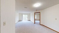 Located at 17285 W River Birch Dr in Brookfield, Wisconsin, this single-floor residence offers four bedrooms, two bathrooms, and a practical, well-organized layout. Throughout the home, neutral cream-colored walls, warm wood trim, and light gray carpeting create a clean and consistent aesthetic.

The generously sized primary bedroom features two warm-toned wooden doors — ideal for a closet and secondary access — along with plush carpeting and ample floor space. The additional bedrooms are bright and carpeted, each with windows that allow natural light to filter in and views of the surrounding greenery.

The galley-style kitchen is equipped with classic oak cabinetry, white countertops, a full-size refrigerator, and wood-look flooring, providing a functional cooking space. The two bathrooms are finished in a clean, simple style — one features a full tub/shower combo with chrome fixtures, while the other includes an oak vanity with a lighted mirror and tile flooring.

A standout feature of this home is the private balcony, accessible from the main living area via a sliding glass door. The balcony overlooks a landscaped courtyard with mature trees, a gazebo, and open green space, offering a peaceful outdoor retreat. The living area itself is open and airy, with sliding door access enhancing the connection to the outdoors.