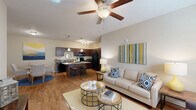 Located at 3245 Glenn McConnell Pkwy in Charleston, SC, this well-appointed 2-bedroom, 3-bathroom residence offers a thoughtfully designed single-floor layout. The open-concept living and kitchen area serves as the heart of the home, featuring warm hardwood-style flooring, neutral tones, and a ceiling fan that adds both style and comfort. The kitchen is outfitted with dark espresso cabinetry, black appliances including a refrigerator, range, and microwave, granite-style countertops, a double stainless steel sink, and a built-in wine rack — all complemented by a breakfast bar with seating. The living area flows seamlessly from the kitchen, offering generous wall space and natural light. The primary bedroom is a comfortable retreat with plush carpet, large windows that invite natural light, and access to a dedicated closet. The second bedroom mirrors this comfortable aesthetic. Three full bathrooms are distributed throughout, each featuring wood-style flooring, dark vanity cabinetry, and tub-shower combinations with clean white tile surrounds. A dedicated in-unit laundry area with a full-size washer and dryer adds everyday convenience, while three closets throughout the home provide ample storage.