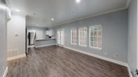 This single-floor residence offers a thoughtfully designed layout that balances comfort and modern functionality. The open-concept living area is finished with durable wood-style flooring and neutral gray walls, creating a clean, contemporary aesthetic throughout. Crown molding and recessed lighting add refined architectural detail, while multiple windows and French doors bathe the space in natural light and provide outdoor views of surrounding greenery.

The kitchen is a standout feature, equipped with stainless steel appliances including a refrigerator and electric range, crisp white cabinetry, white quartz countertops, and a peninsula with an undermount sink — ideal for both cooking and casual dining. Marble-style tile flooring completes the kitchen's polished look.

The bedroom is generously proportioned, featuring a ceiling fan, crown molding, and an arched window that invites abundant natural light. It is complemented by a half-bath vanity area with ample storage and access to a closet.

The full bathroom is finished with white subway tile, a tub-shower combination, and classic mosaic tile flooring, while the half-bath offers a white vanity with storage cabinets and matching mosaic tile. An in-unit laundry area adds everyday convenience, rounding out this well-equipped and move-in-ready residence.