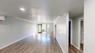 Located at 2001 S Haster St in Anaheim, California, this single-story residence offers a clean, modern interior with a cohesive neutral color palette throughout. The open living area is bright and generously proportioned, featuring durable hardwood-style flooring, a textured ceiling, and recessed lighting. Large glass doors and a paneled entry door allow natural light to pour in, creating an airy and welcoming atmosphere.

The kitchen is well-appointed with white shaker-style cabinetry extending to the ceiling for ample storage, granite-style countertops, a stainless steel sink, and a gas range. Recessed lighting and a window with vertical blinds keep the space bright and functional.

The bedroom is a comfortable, quiet retreat with hardwood-style flooring and direct access to a walk-in closet outfitted with dual shelving and hanging rods along two walls. The bathroom features a granite-style vanity countertop, a full tub-shower combo, and recessed lighting in a clean, light-toned finish.

Outside, a private patio area offers a concrete surface bordered by lush greenery and a white wood fence, providing a pleasant and low-maintenance outdoor space. The overall design is fresh, streamlined, and move-in ready.