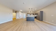 Located at 4328 Provision Parkway in Fort Wayne, Indiana, this modern single-floor residence showcases a thoughtfully designed open-concept layout finished with light wood-tone luxury vinyl plank flooring throughout. The expansive living area flows seamlessly into the kitchen, creating a bright and cohesive living space. The kitchen is a standout feature, equipped with sleek taupe flat-front cabinetry, stainless steel appliances including a full-size refrigerator, electric range, microwave, and dishwasher, along with a marble-patterned tile backsplash, white quartz countertops, and a central island with pendant lighting overhead. A sliding glass door in the living area opens to a private balcony offering open outdoor views. The bathroom is appointed with wood-look tile, a frameless glass walk-in shower with floor-to-ceiling tile surround, matte black fixtures, and a wood-toned vanity. Additional rooms offer clean, neutral interiors with ample natural light and open floor plans suitable for flexible use. A walk-in closet with wire shelving provides generous built-in storage. Recessed lighting, a textured ceiling, and consistent modern finishes contribute to the polished, contemporary ambiance of this well-appointed space.