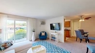 Located at 131 Kings Park Dr in Liverpool, NY, this well-appointed 2-bedroom, 1-bathroom unit offers a thoughtfully designed single-floor layout. The open living room is bright and welcoming, featuring large sliding glass doors that invite generous natural light and views of the surrounding greenery. Plush carpeting runs throughout the living and sleeping areas, adding warmth and comfort underfoot. The kitchen is efficiently laid out in a galley style, showcasing warm wood cabinetry, dark granite-style countertops, a tile floor, and white appliances — all complemented by a window that keeps the space bright. The spacious primary bedroom comfortably accommodates a full suite of furniture and includes a ceiling fan and a window for natural light. The second bedroom is equally inviting, featuring its own closet and easy hallway access. The bathroom is clean and functional, with tile flooring and a vanity with ample counter space. A dedicated closet provides additional storage. Throughout the unit, the neutral color palette and soft carpeting create a calm, cohesive ambiance, making this a practical and comfortable residence in a well-established Liverpool neighborhood.
