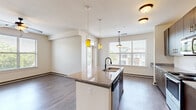 This single-floor residence offers four bedrooms and two bathrooms within a well-designed, open-concept layout. The combined kitchen and living area serves as the heart of the home, featuring a central island topped with granite countertops and an undermount sink with pendant lighting overhead. Dark-toned cabinetry lines the kitchen walls, complemented by a subway tile backsplash and a full suite of stainless steel appliances, including a range, microwave, and refrigerator. Wood-style flooring extends throughout the main living areas, contributing to a cohesive, contemporary aesthetic. Multiple windows allow natural light to fill both the kitchen and living spaces, offering views of the surrounding greenery.

The primary bedroom is a generously sized retreat, carpeted for comfort and equipped with a ceiling fan. It connects directly to a private bathroom featuring a double-sink vanity with granite countertops and a tub-shower combination, as well as a spacious walk-in closet outfitted with multi-level wire shelving. The additional bedrooms are carpeted or finished with wood-style flooring, each with ceiling fans and windows. The second full bathroom mirrors the refined finishes found throughout, with a granite vanity and tub-shower combo.