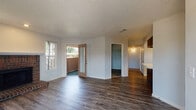 Located on Dublin Blvd in Colorado Springs, CO, this single-floor residence offers a well-designed layout with a range of functional and stylish features throughout. The open living area is a highlight, showcasing durable wood-style flooring, neutral-toned walls, and a classic brick fireplace that serves as a natural focal point. Natural light filters in through multiple windows, and a glass-paneled door leads directly to a private outdoor patio, seamlessly connecting indoor and outdoor living. An adjacent area provides additional flexible space, with a closet and hallway leading further into the home. The kitchen is thoughtfully appointed with rich, dark espresso cabinetry, light stone-look countertops, white appliances including a refrigerator, electric range, microwave, and dishwasher, plus a double-basin sink beneath a window. The bedroom features plush carpet flooring, a ceiling fan with light fixture, and a window with outdoor views, creating a comfortable and restful retreat. The bathroom includes a dark vanity with a light countertop, a tiled shower-tub combination, and wood-style flooring. Throughout the residence, textured ceilings and clean white trim provide a cohesive, classic aesthetic.