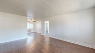 Located at 2770 Atlanta Ave in Riverside, CA, this single-floor, 2-bedroom, 1-bathroom home offers a practical and well-maintained living space. Rich, dark hardwood-style flooring runs consistently throughout, lending warmth and cohesion to every room.

The living room is welcoming, featuring a classic wood-paneled front door with an arched transom window that draws in natural light. The open layout connects seamlessly to the kitchen, which stands out as a highlight of the home. It is outfitted with dark espresso cabinetry, granite-look countertops, stainless steel appliances including a refrigerator and range, a built-in dishwasher, and a striking stainless steel island range hood. A breakfast bar provides additional counter space and casual seating.

Both bedrooms are finished with the same hardwood-style flooring and crisp white walls. They feature low horizontal windows dressed with vertical blinds, and one bedroom includes a wall-mounted air conditioning unit and a spacious closet. The bathroom is cleanly designed with large-format stone-look tile surrounding a full soaking tub and shower combination, complemented by a bright window and white fixtures.

A connecting hallway links the private areas of the home efficiently. The overall aesthetic is clean, neutral, and move-in ready.