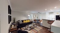 Located at 3700 S Sepulveda Blvd in Los Angeles, this single-floor residence offers a thoughtfully designed layout with a cohesive contemporary aesthetic. Rich hardwood flooring flows throughout, tying together each space with warmth and continuity.

The open-concept living and dining area serves as the heart of the home. The living room features crown molding, recessed lighting, and a generous sectional sofa accented with bold yellow throw pillows. A glass-top coffee table and layered area rug add depth, while framed artwork adorns the walls. The dining area sits adjacent, centered around a round dark-topped table with cognac leather chairs, a ceiling fan overhead, and vertical blinds filtering natural light.

The kitchen is well-appointed with white shaker cabinetry, dark countertops, subway tile backsplash, stainless steel appliances, and a breakfast bar with modern counter seating. A fireplace is visible from the kitchen, adding a notable architectural feature to the common area.

The bedroom is a calm retreat with dark hardwood floors, a substantial wood-framed bed, and ample natural light from a window with vertical blinds. A walk-through leads to the bathroom, which features a clean, bright tub-shower combination with a glass sliding door and crisp white finishes.